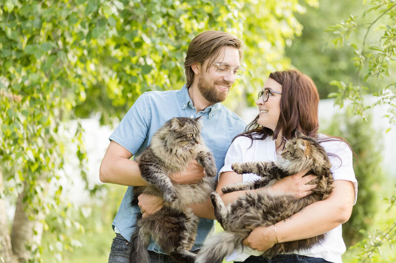 Aubre outside with husband and two cats posing in front of a birch tree