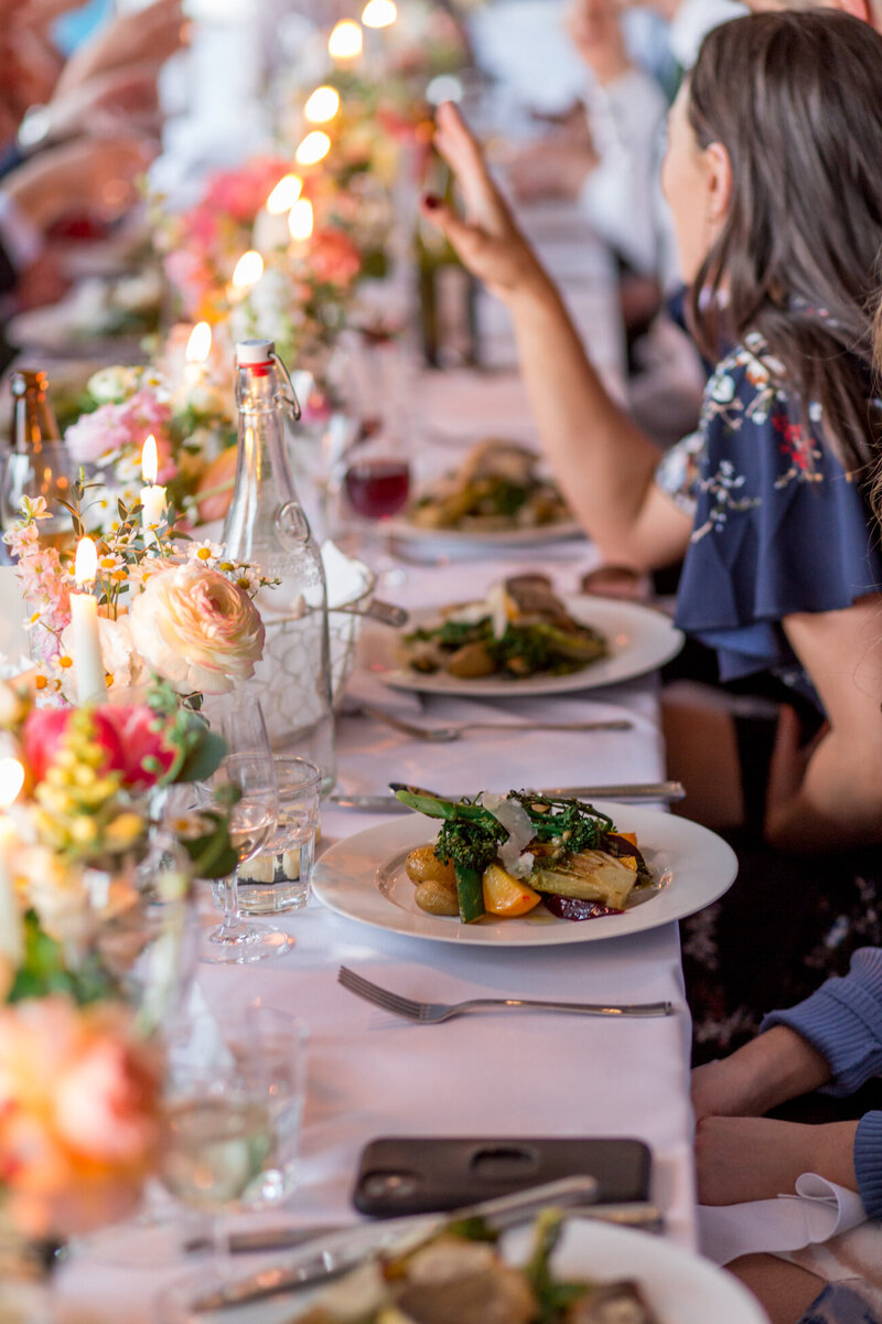A long dining table with flowers and atmospheric candles and plates of delicious food