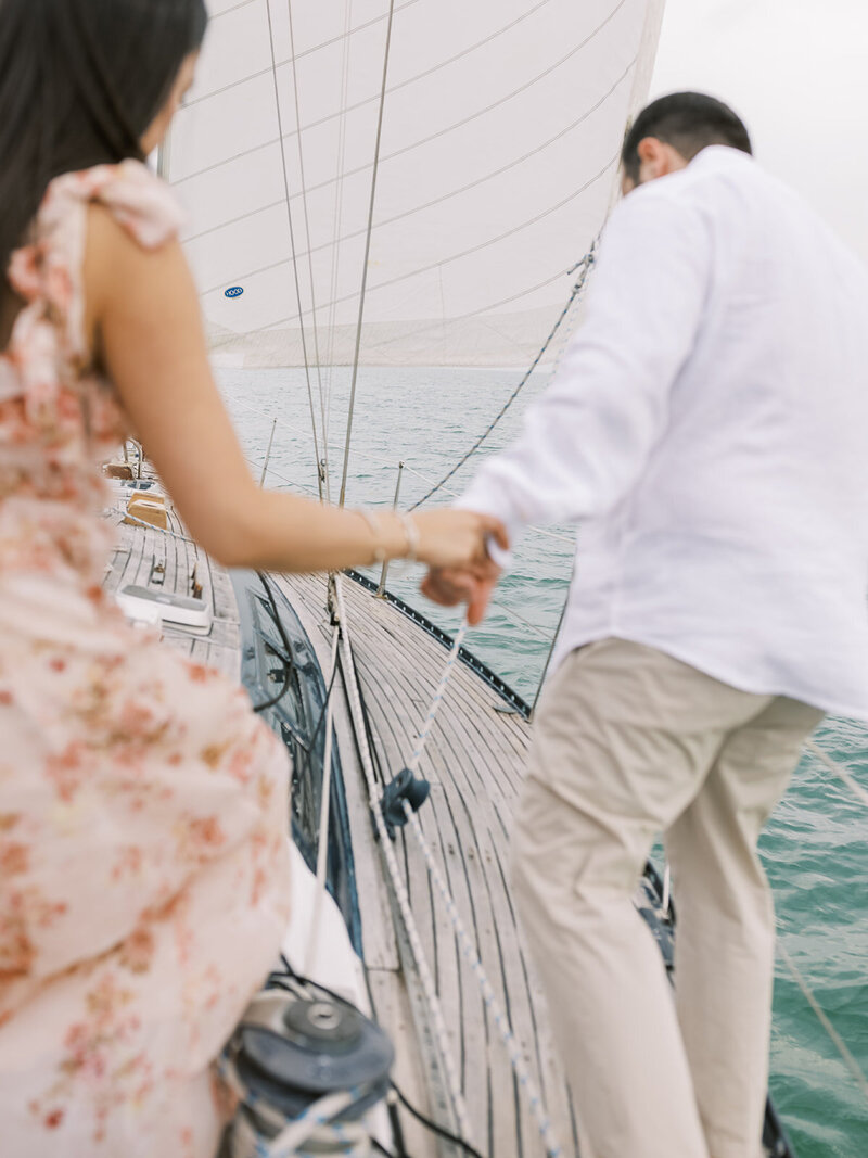 A couple walk around a sailboat during their engagement session in Miami Beach, Florida