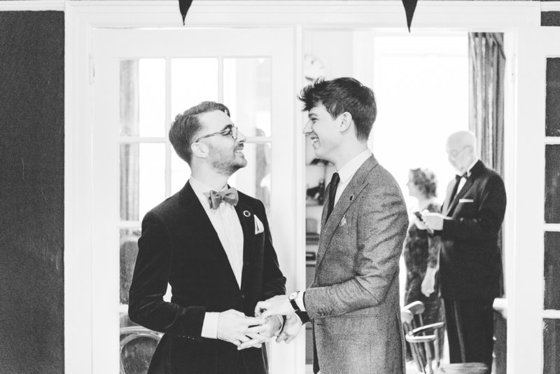 grooms smile at each other while getting ready