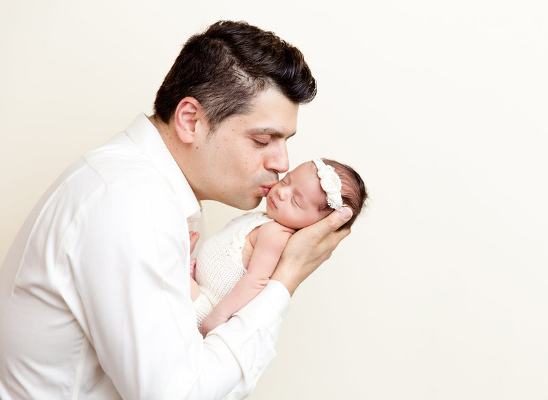 Dad with newborn baby girl kiss on the cheek