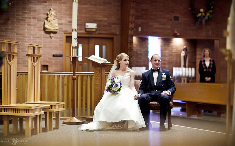 Couple sits on their own seating at a catholic wedding ceremony at St. John's in Longmont Colorado