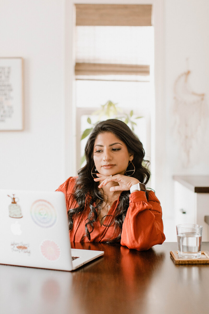 Mindfulness coach Radhika sitting at a table looking at a laptop