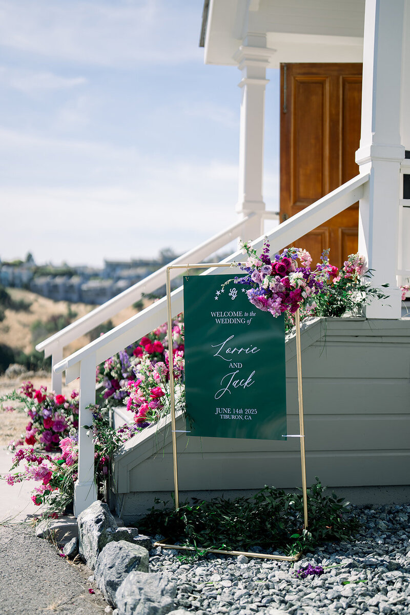 Green wedding welcome sign with bold floral installation outside coastal home in Tiburon CA captured by California wedding photographer