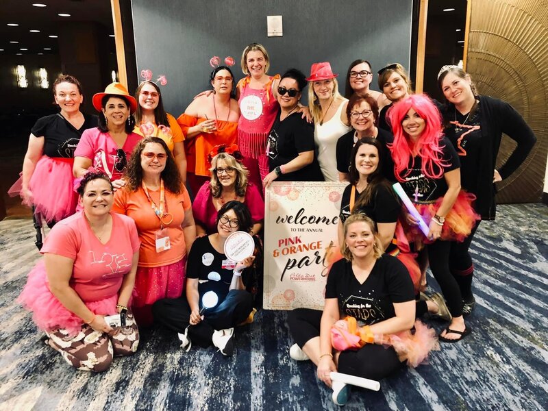 Group of women dressed in pink and orange with silly props