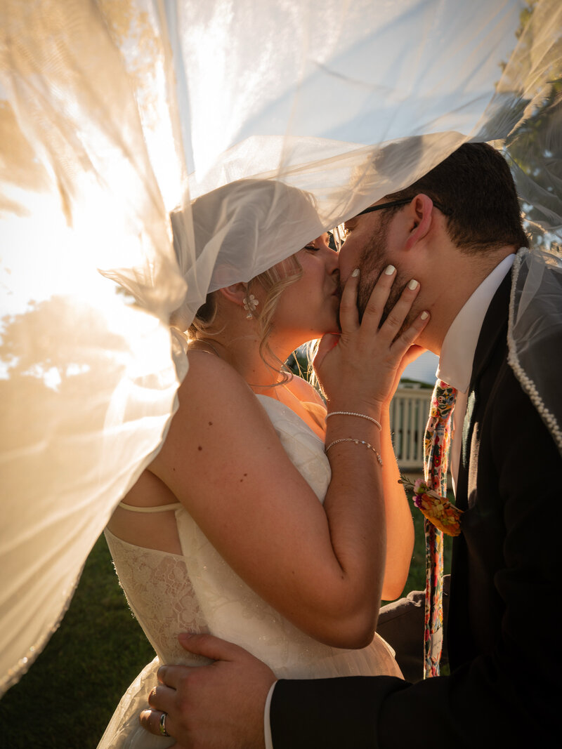 Bride and groom sharing a candid moment under the veil during their wedding portraits photographed by Ferrazzani Photography.