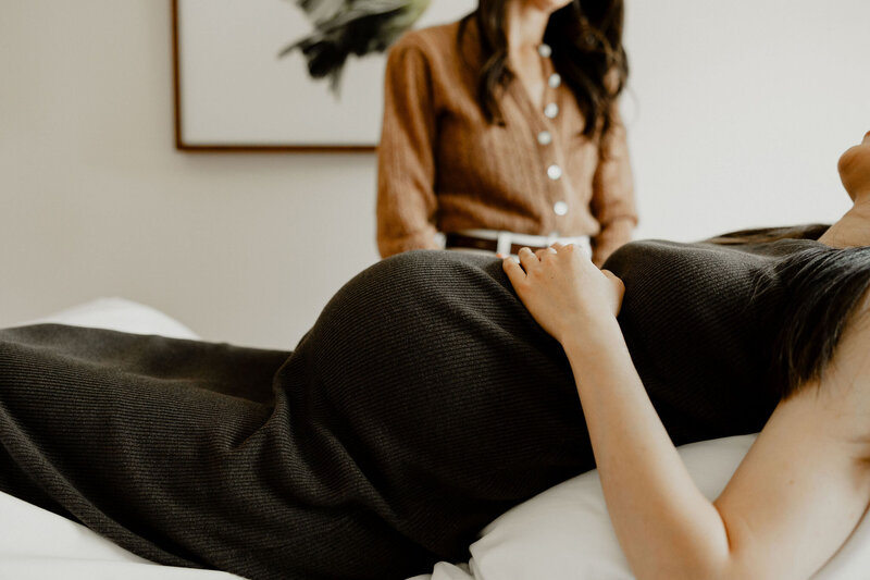 Close-up of an acupuncturist placing fine needles into a patient’s lower abdomen during a gentle fertility acupuncture session