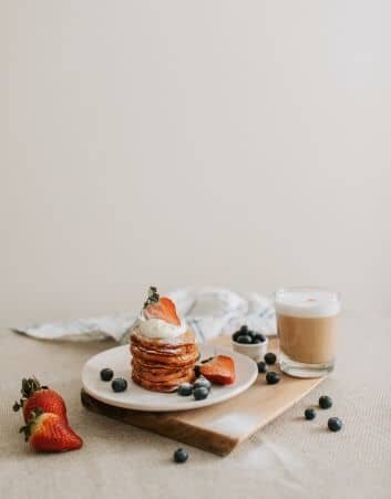 pancakes-topped-with-strawberries-whip-cream-blueberries-with-a-coffee-mug