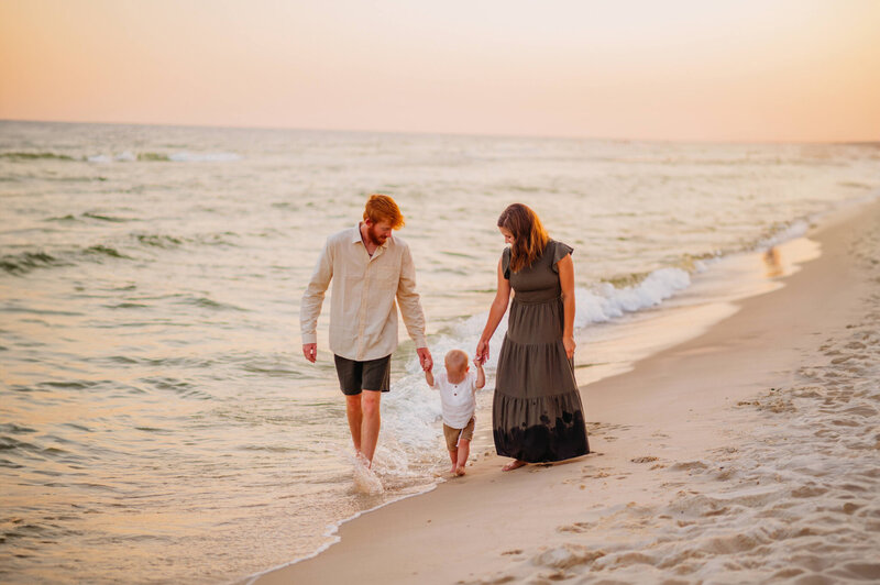 photo of family with a toddler walking on the beach