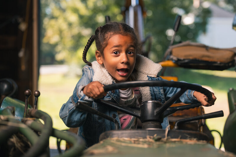Young girl on tractor making a silly face having a fun family photo session