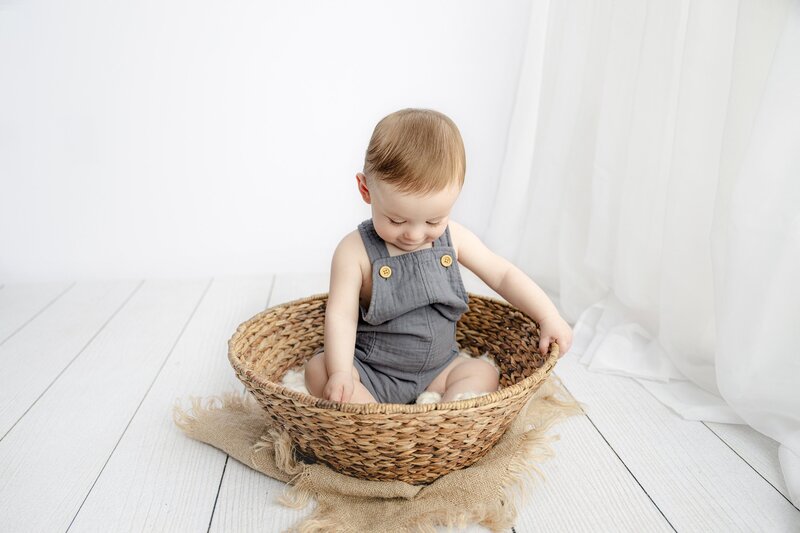 little seven month old looking down at a brown basket