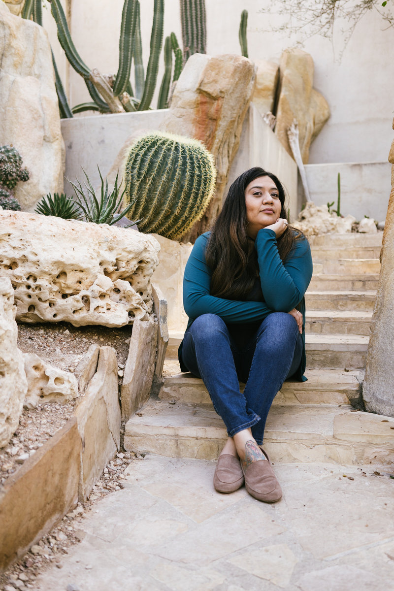 San Antonio Photographer Irene Castillo sitting on stairs surrounded by succulents and cactus