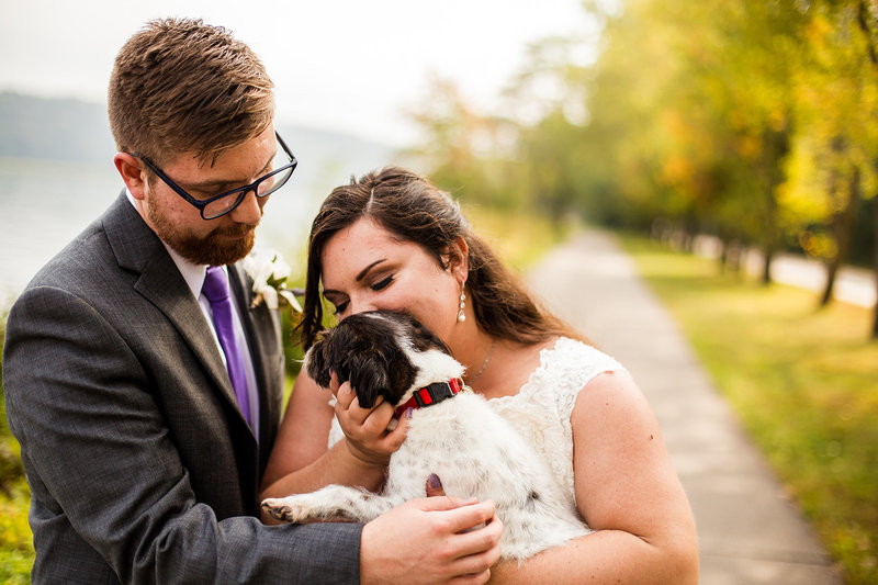 Bride and groom snuggle their small dog at Presque Isle State Park