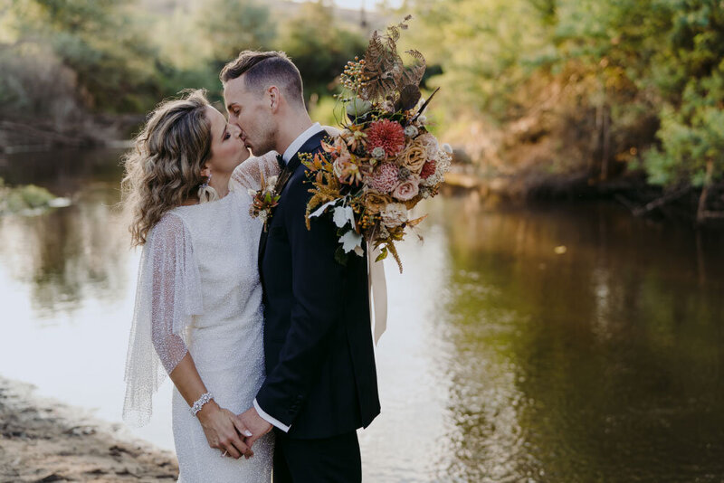 Bride and groom kissing at the river at the Riverstone Estate in the Yarra Valley