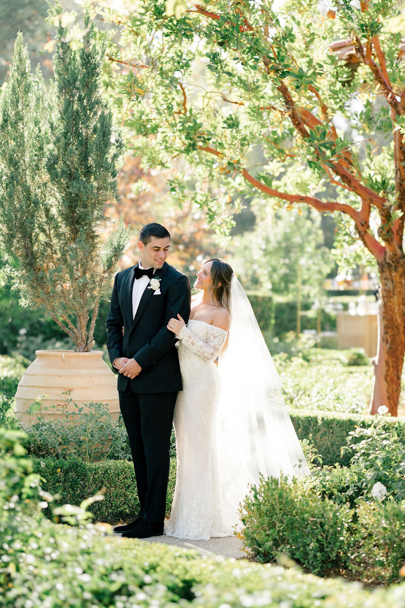 Wedding reception tables set up in an outdoor arched corridor overgrown with ivy