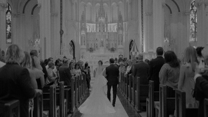 person in wedding dress walking down aisle in catholic church