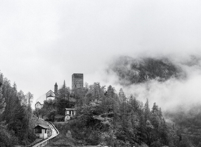 black and white film photograph of small village in the clouds
