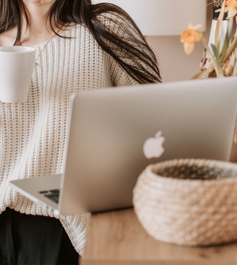 A close up of a woman standing next to a laptop as she holds a cup of coffee. This could represent a client starting online couples therapy in Miami, FL and all of Florida. We offer online couples counseling, online marriage counseling, and other services. Contact us to learn more today.