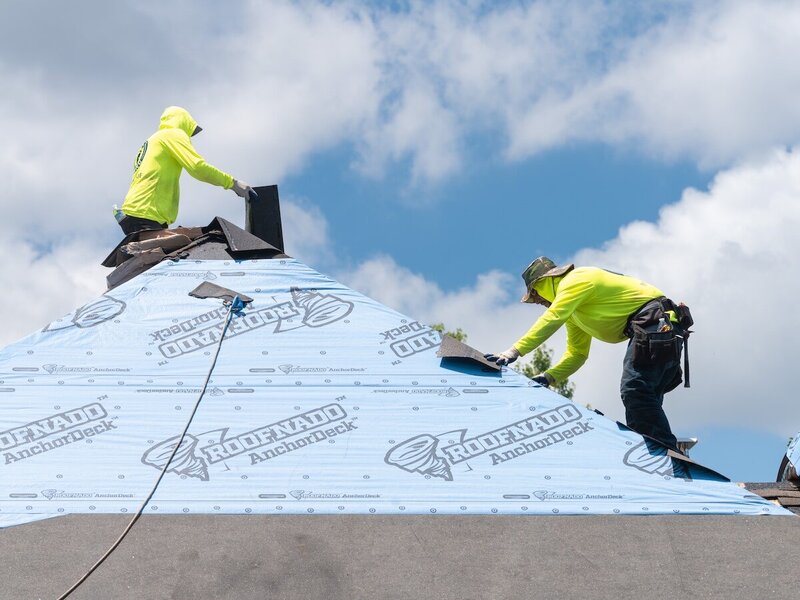Two men working together to replace a Kansas City roof with new shingles