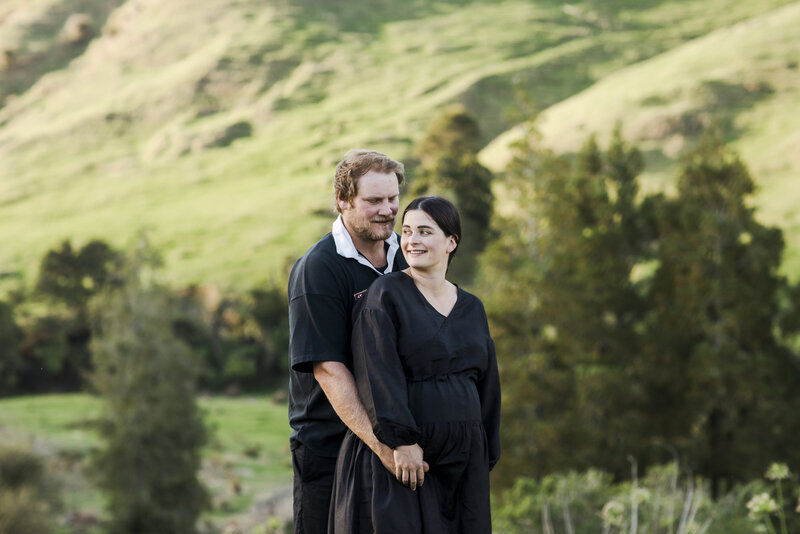pregnant couple snuggling in rural setting