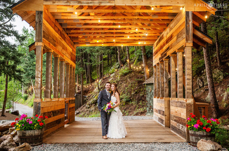 Cute photo of bride and groom under covered bridge at Blackstone Rivers Ranch in Idaho Springs