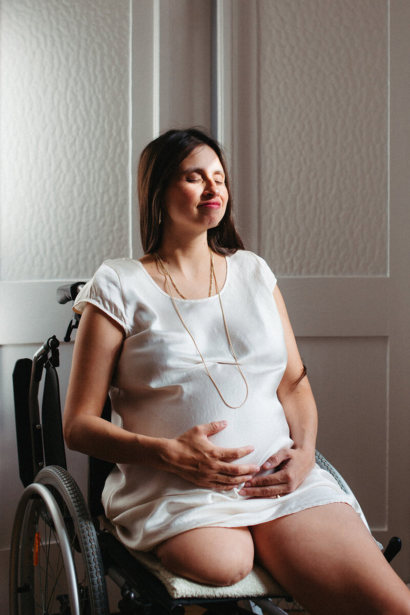 schwangere frau mit babybauch im rohlstuhl und behinderung