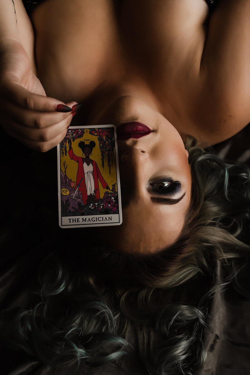 boudoir client laying on bed holding tarot card