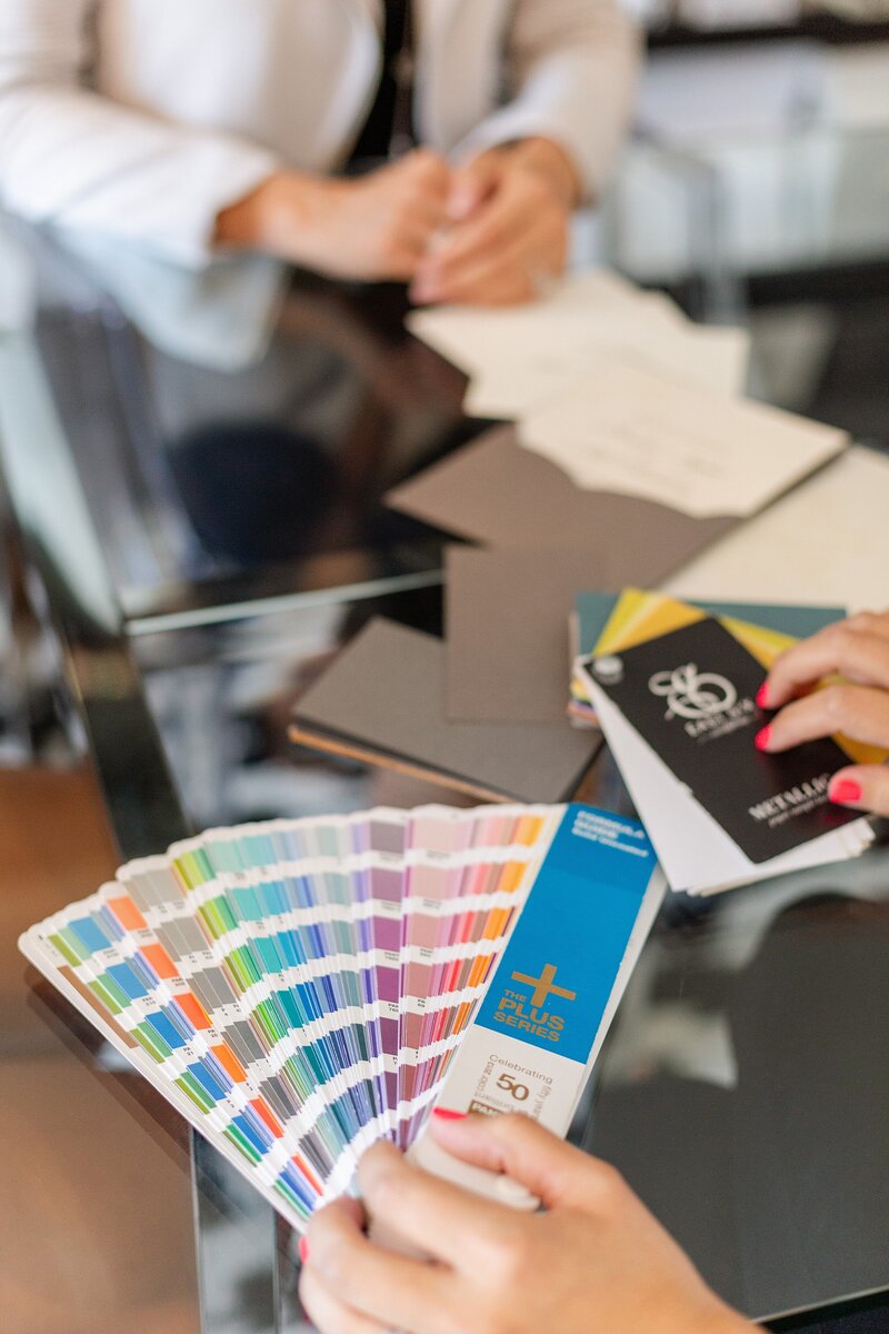 luxury wedding invitation designers in Sherman Oaks holds out Pantone color swatches during design session
