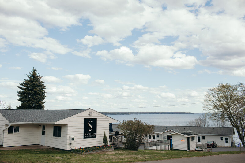 white motel building with a large Seagull Bay logo on the side. Views of Lake Superior and the Apostle Islands are in the background.