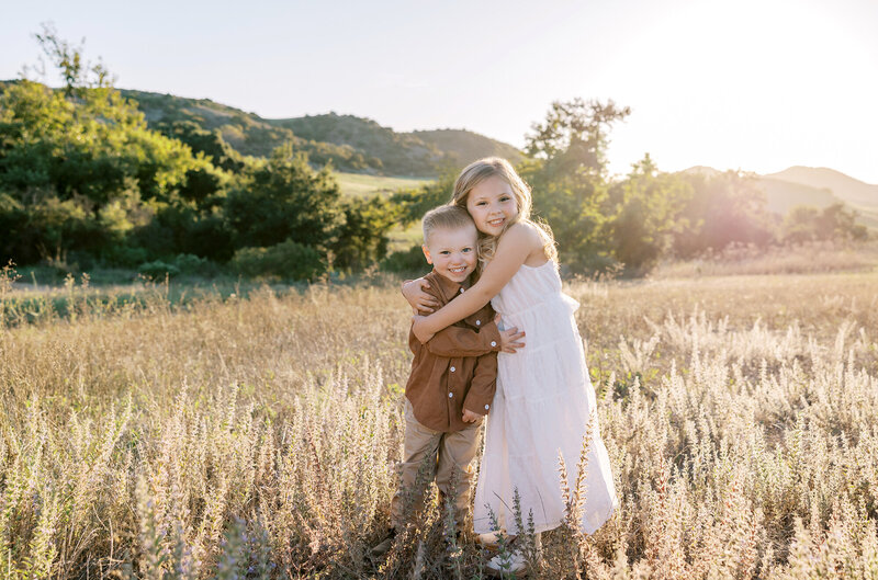 Siblings hug each otherin a golden field during their Los Angeles child photography session