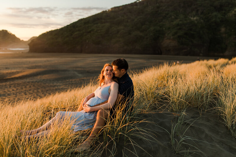 pregnant couple in dunes at sunset