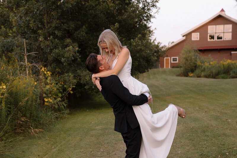 groom lifting the bride at barnwood events, a wedding venue in madison, winconsin.