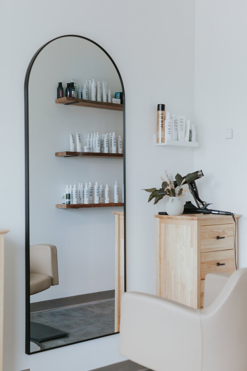 Environmental brand photo of hair stylist salon scene with mirror, salon chair, hair tools, & hair products in South Charlotte