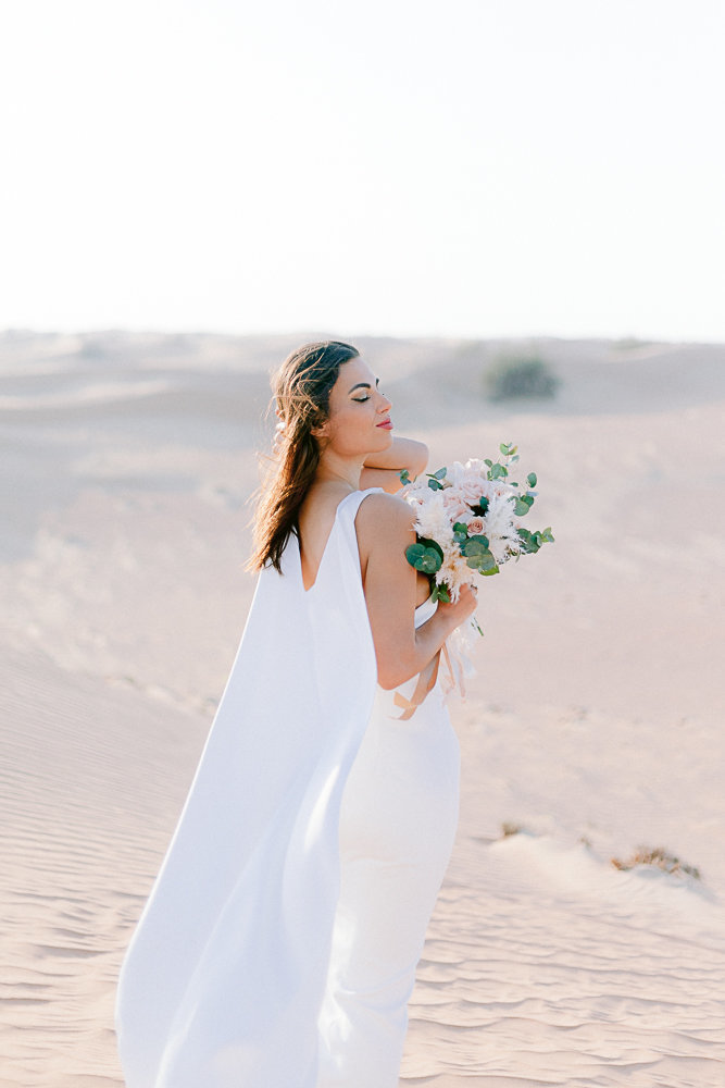 bride looking at the sky with a bouquet in lahbab desert in duabi amirat Arab United