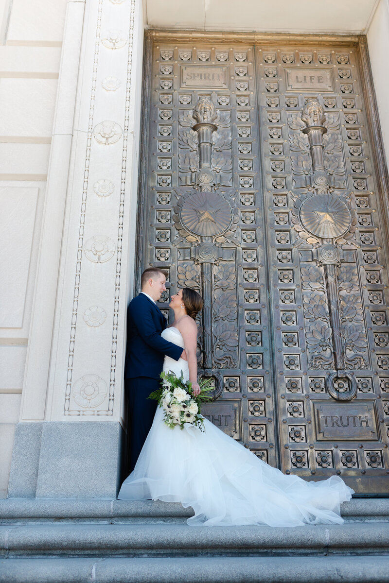 bride and groom gazing into each other's eyes in front of gold doorway