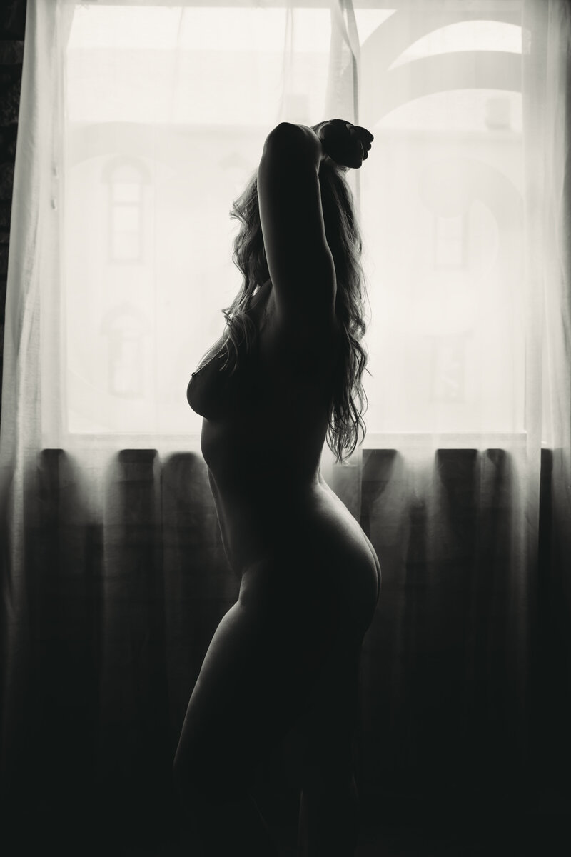Black and white silhouette boudoir portrait with window backlighting in-studio