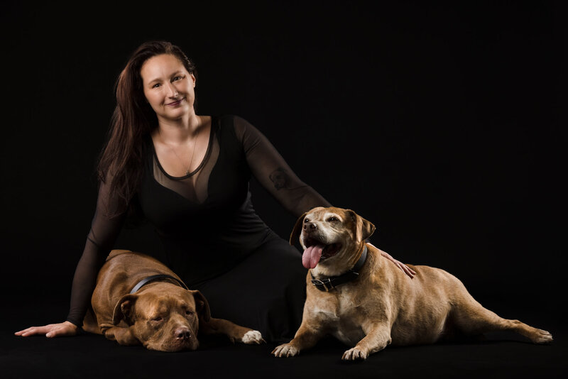 LGBT Worcester and Boston based Photographer wearing a green gown sitting with her Boxer mix senior aged dog