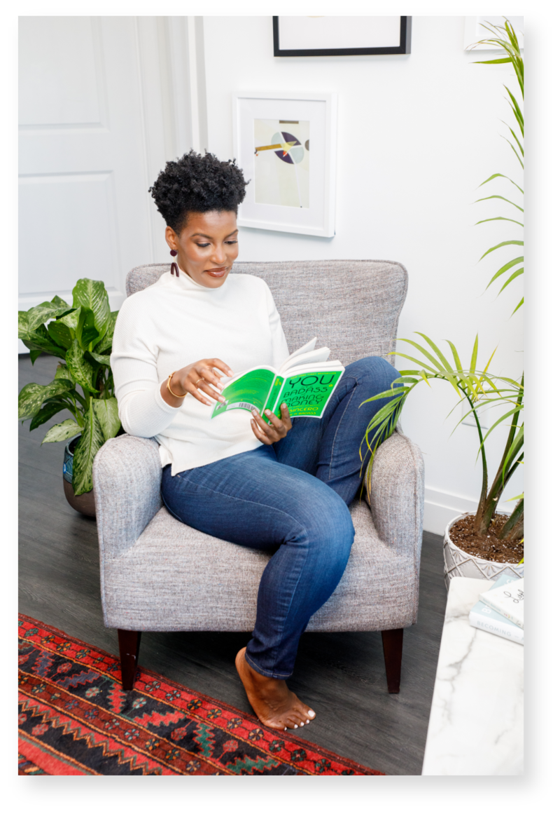 Woman with short and curly hair reading while sitting down on a gray chari