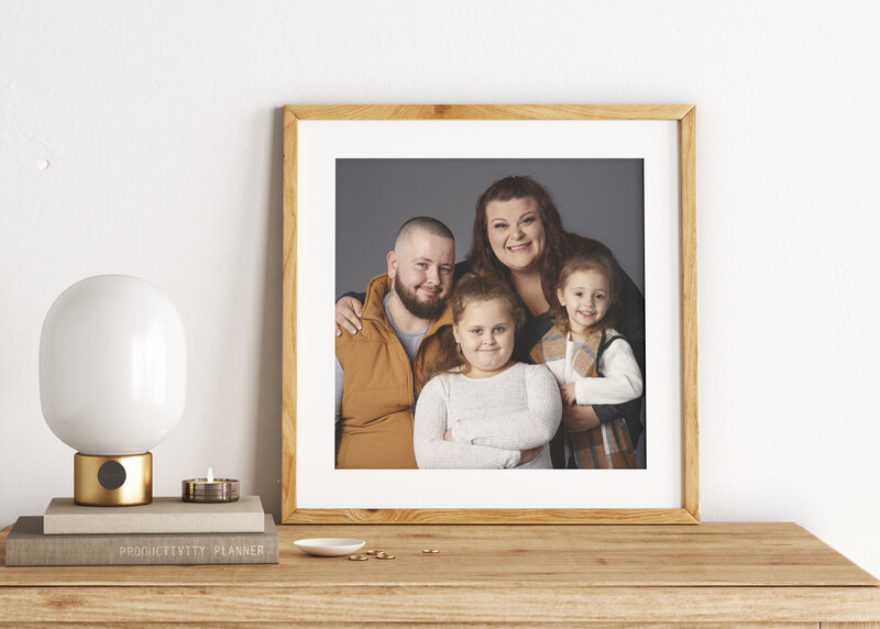 Framed portrait of a family of four sitting on a wood desk