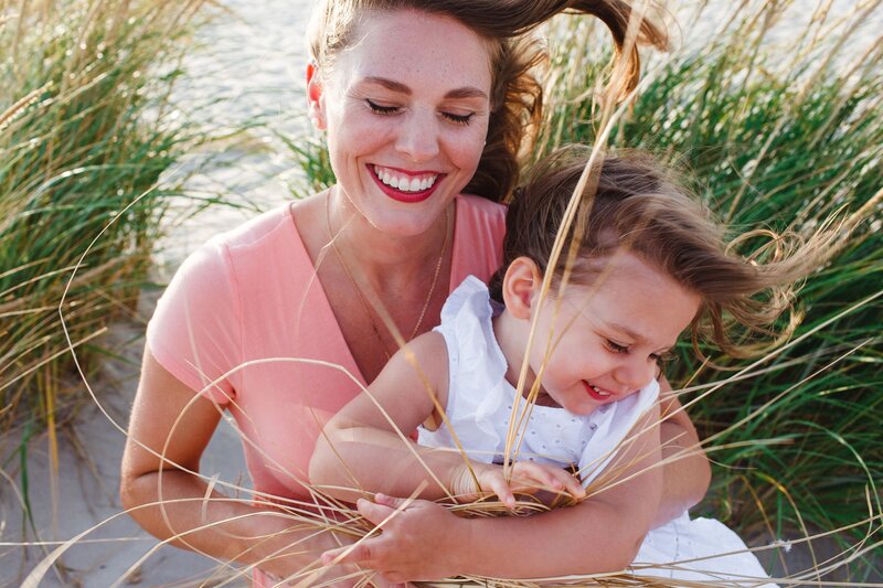 Mom holding young girl on beach