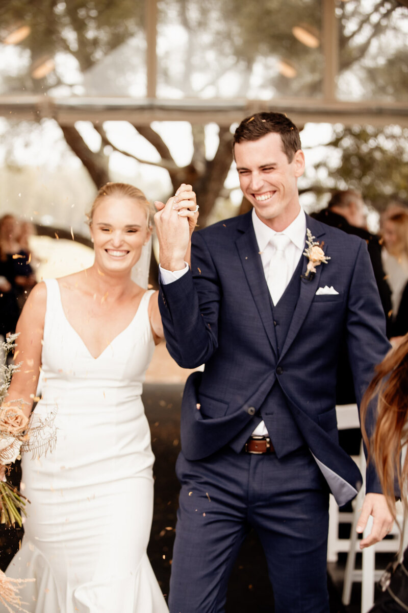 Newly weds walks down the aisle with while guests throw confetti