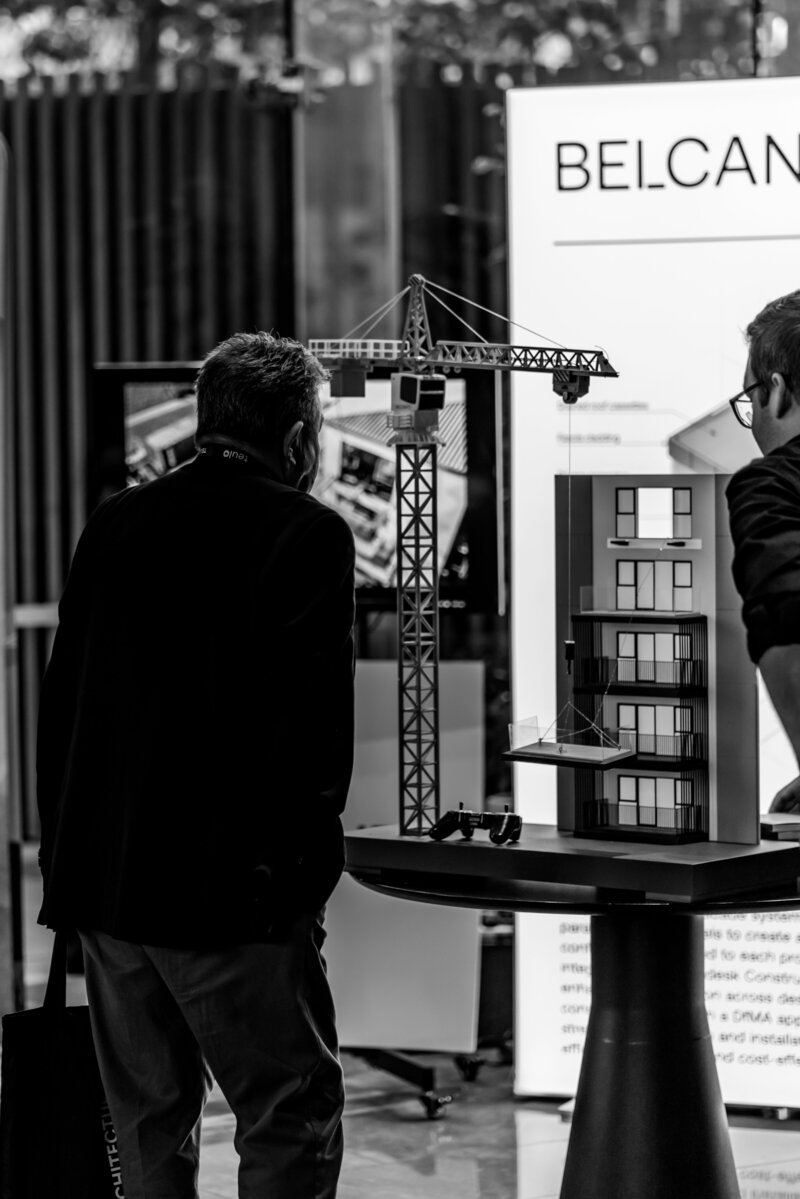 A black and white image of a man looking at a toy design crane at an architectural event by Auckland Event Photographer Zanthe Vorsatz