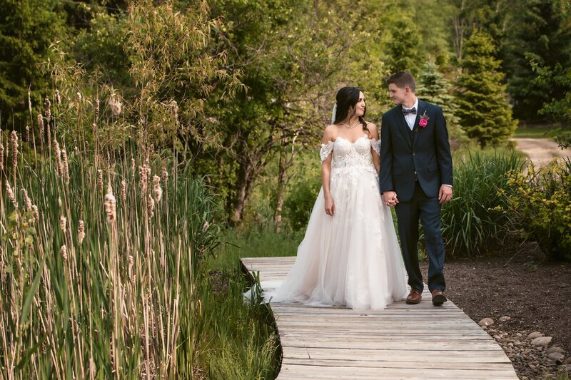 bride and groom holding hands walking on a path