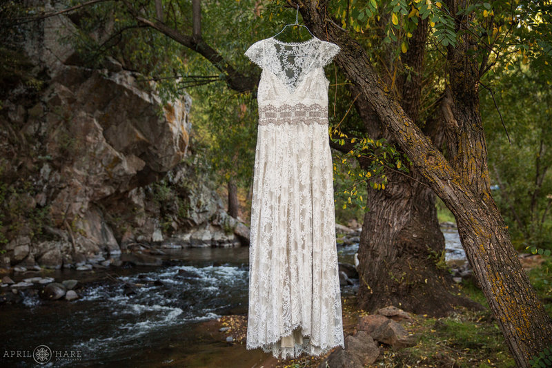 Wedding dress hangs from a tree next to the beautiful Bear Creek in Evergreen Colorado