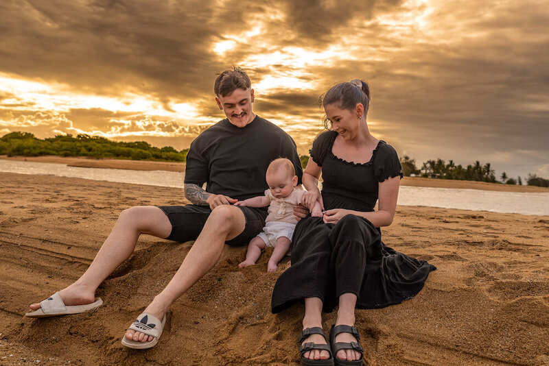young family of three sitting on the beach at sunset -  townsville child milestone photography by Jamie Simmons - Simmons Memorable Moments