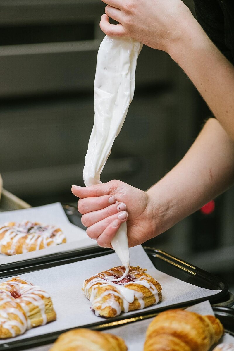 hands icing a pastry in a bakery