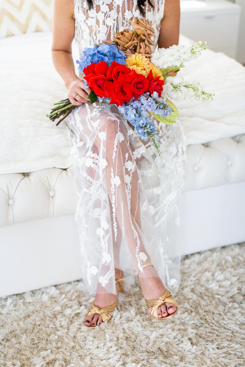 Modern bride with golden shoes and colourful bouquet