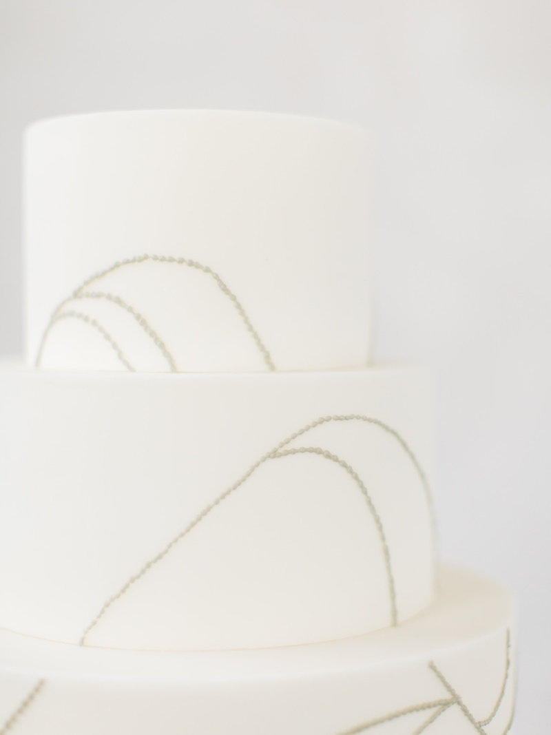 This all white and grey wedding cake is a modern minimal take on a classic with orchid inspired design