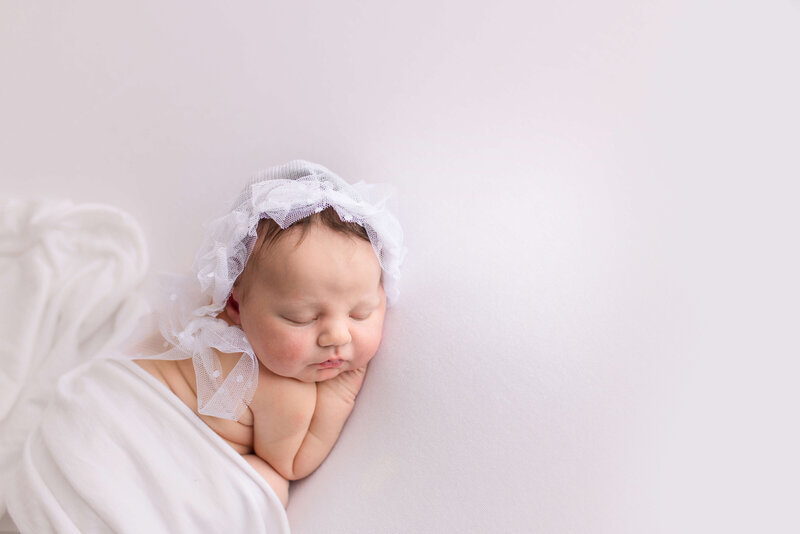baby girl wrapped in white with white lace bonnet