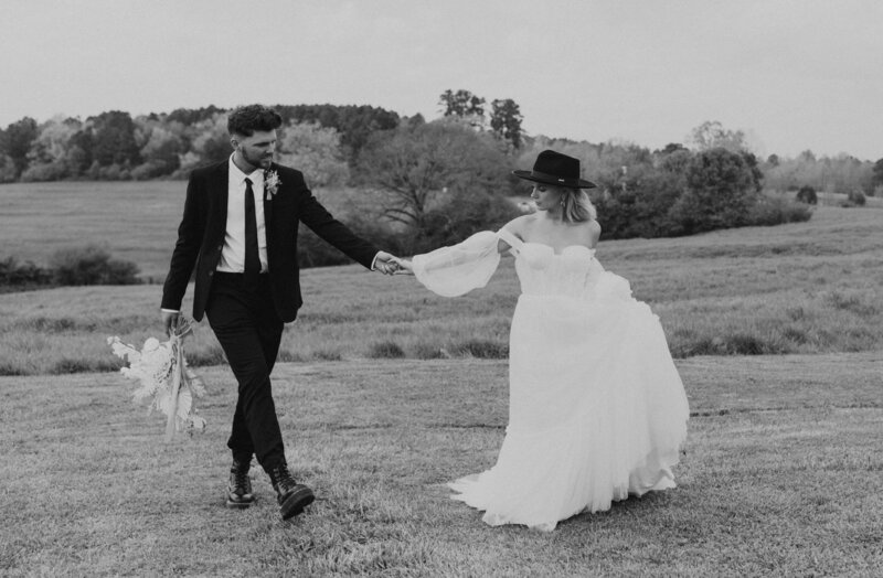 Couple holding hands in a field with a black and white edit